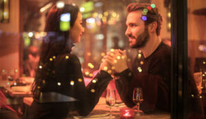 Couple holding hands at a restaurant table and dating after divorce.