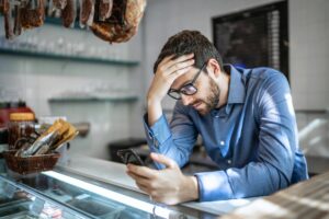 Man in blue shirt sits at a counter with head in his hand as he contemplates the tough questions you must ask yourself before leaving your marriage.