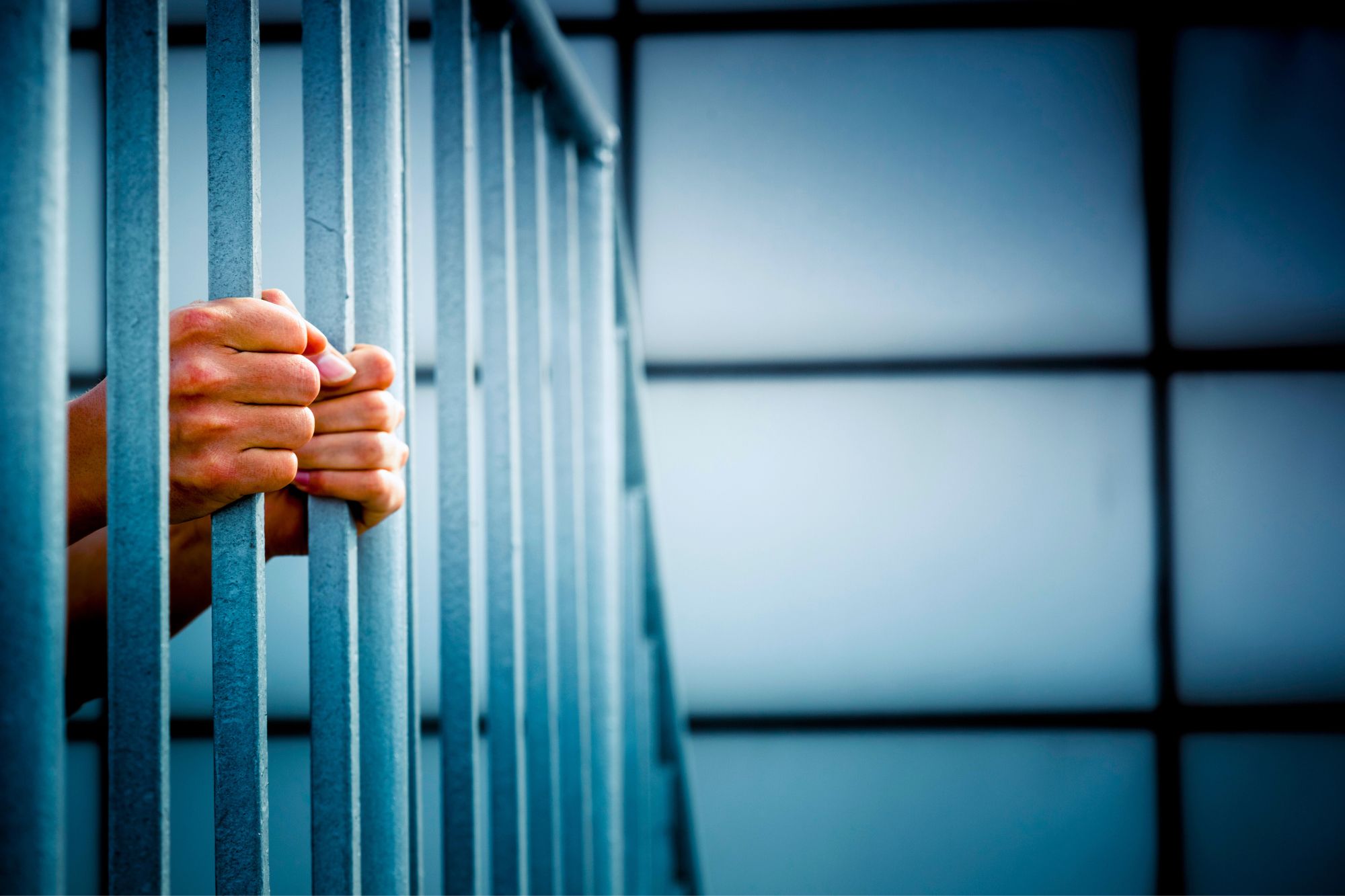 Close up on the hands of a person who feels like a prisoner of an unhappy marriage gripping what looks like jail cell bars.