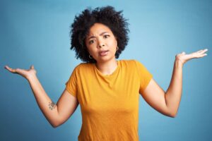 Woman in yellow shirt against a blue background has her arms raised up frustratingly asking "Am I the only one in WTF mode"