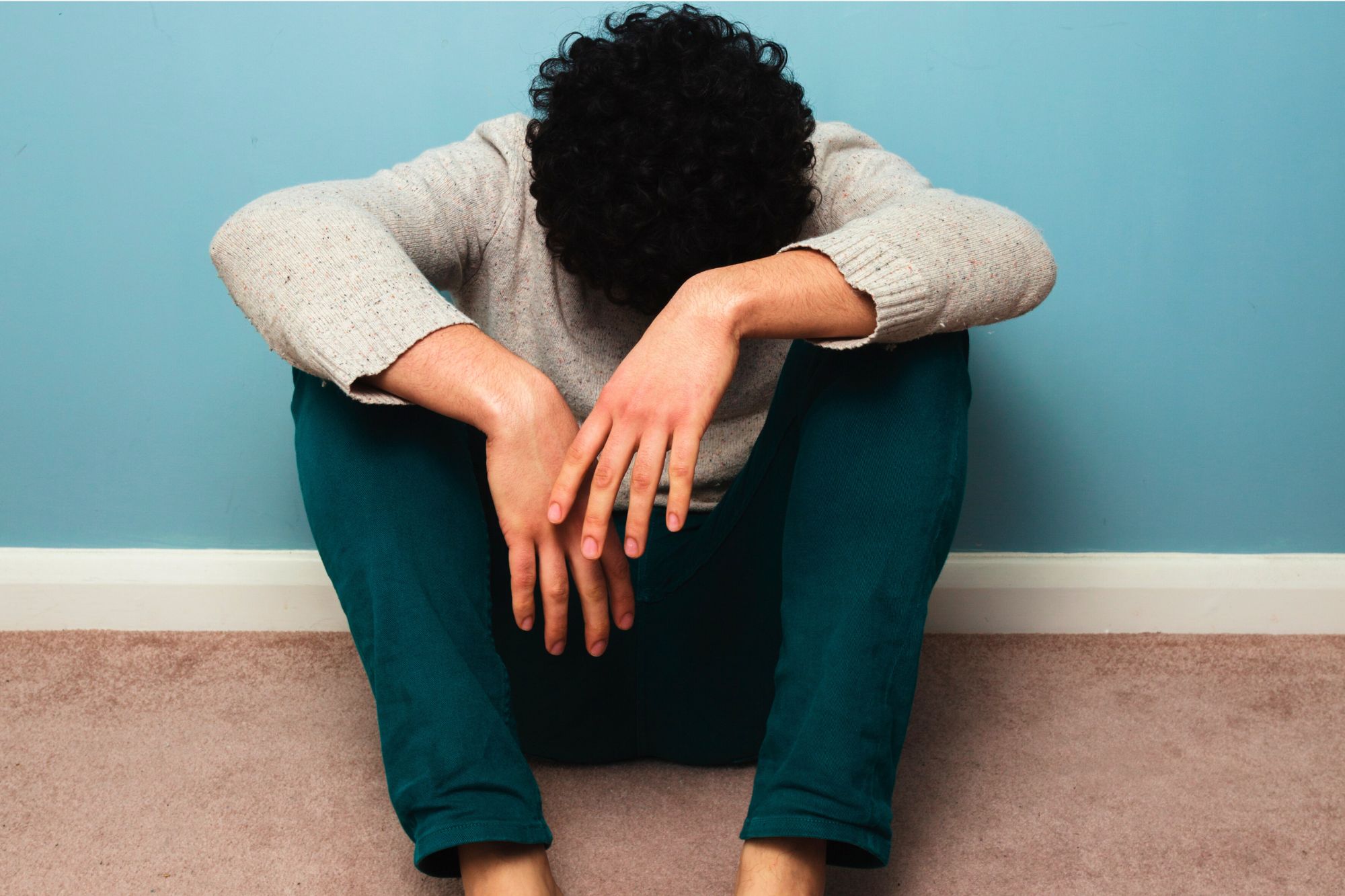 A sad man with his head hanging between his legs as he tries to figure out How To Get Through Grief After A Divorce