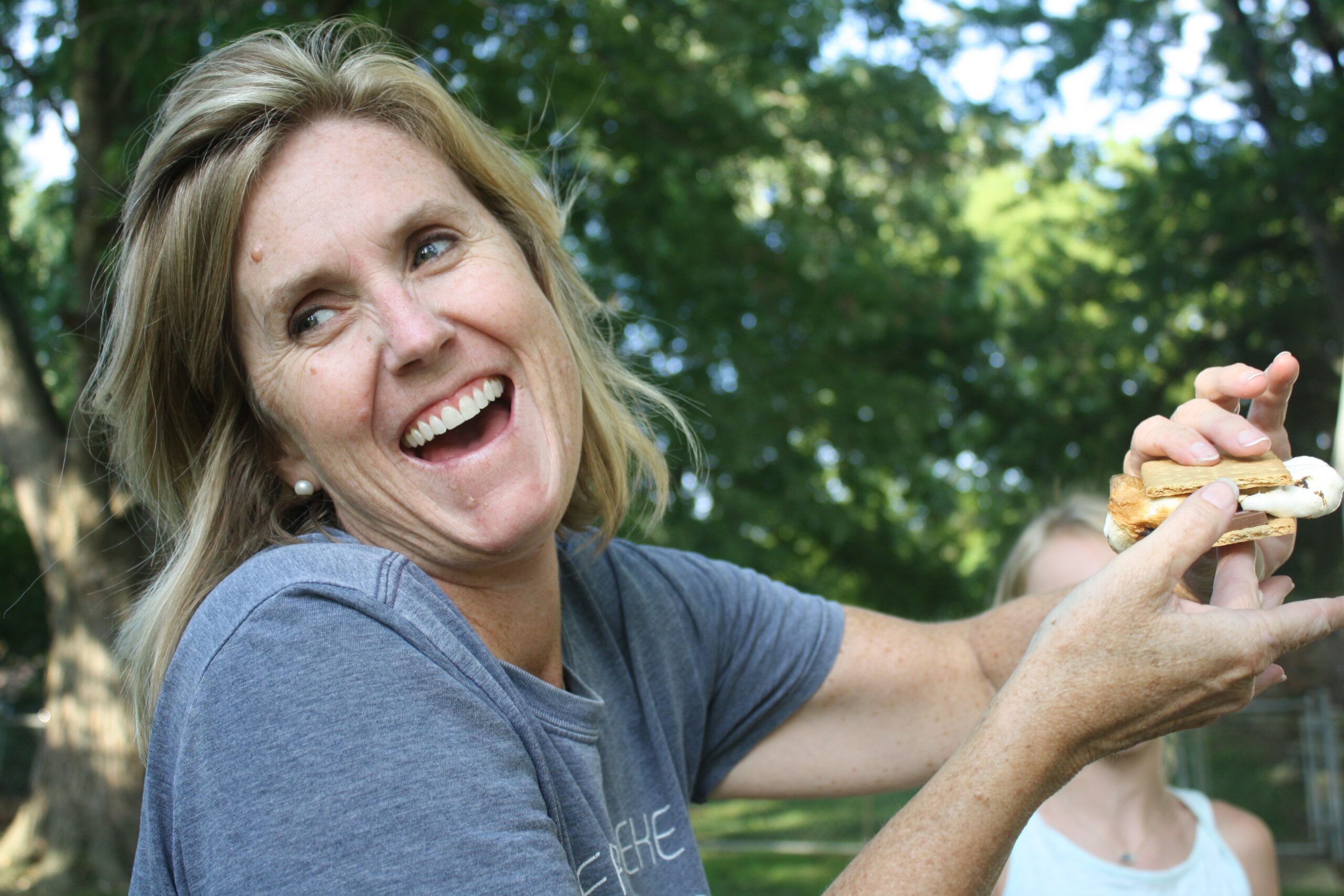 enjoy-your-life-and-be-happy Woman laughing as she struggles with holding a s’more.