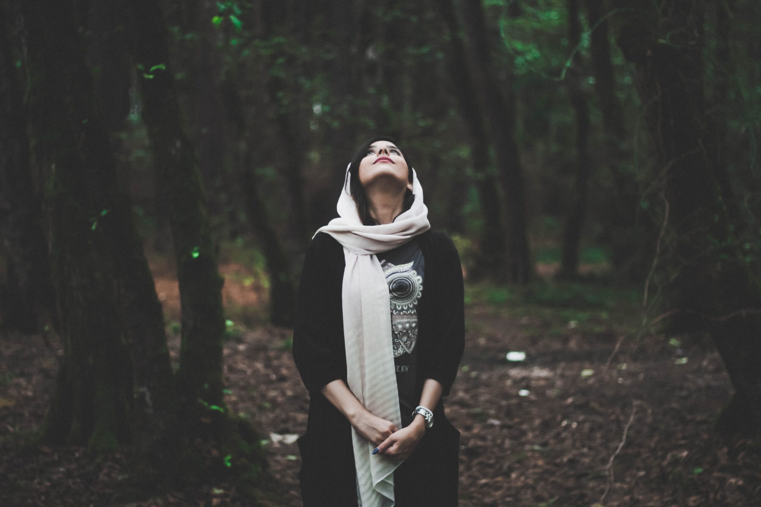 how-can-self-awareness-be-developed Woman looking up while standing in a forest and contemplating her self-awareness.