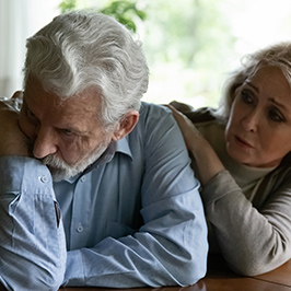 concerned woman comforting man on couch