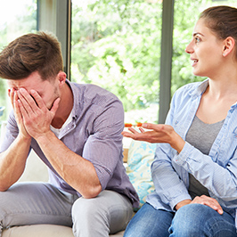 Man with head in his hands while woman speaks beside him.