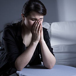 woman in black praying at bedside