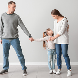 Father pulling at daughter while daughter holds onto mother