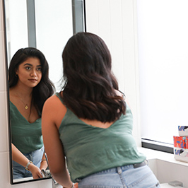 Woman in green looking at herselfin the mirror